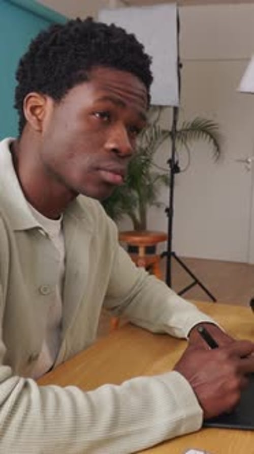 Young African Photographer Retouching Photos with a Graphics Tablet in Studio