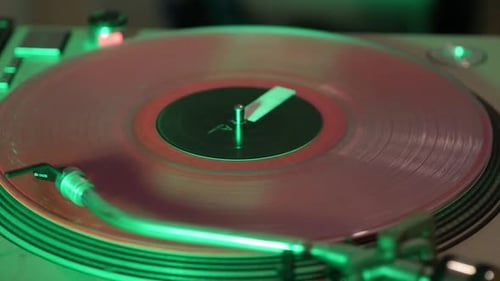 DJ-Plattenspieler, der ein rosafarbenes Vinyl dreht, während farbige Lichter die Kameraschwenke blinken lassen