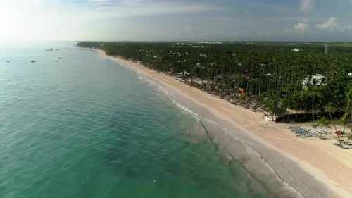 Drone flies over tropical island beach resort coastline on a sunny day