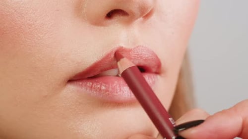 Jeune femme maquillée avec un crayon à lèvres rouge sur ses lèvres, gros plan, d'une femme appliquant du rouge