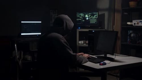 Hooded Hacker Typing Code at Multiple Computers