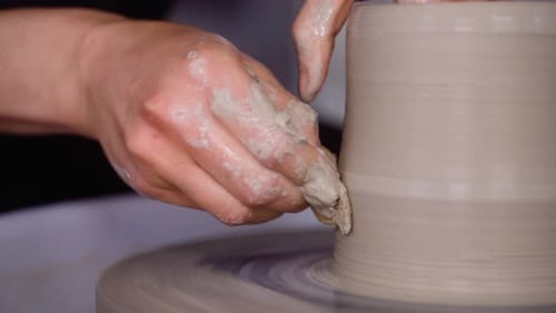 Potter utilise une éponge pour façonner un pot en argile sur son tour de poterie