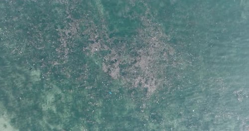 Drone filmé de haut en bas à haute altitude montrant de l'eau polluée remplie de déchets flottant au-dessus d'un cadavre