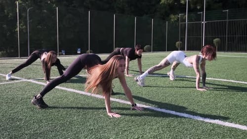 Women Exercise Together in a Park on Athletic Field
