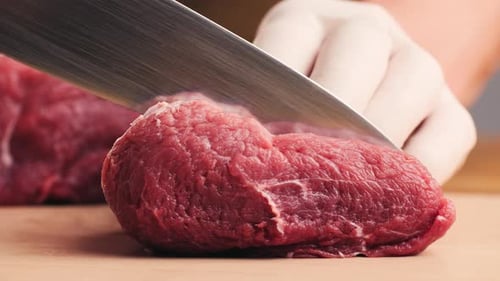 Chef Slicing Fresh Raw Beef on Wooden Board