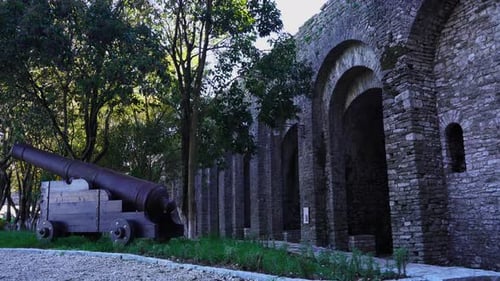 Gun in front of high stone walls outside historic famous castle of Gjirokastra