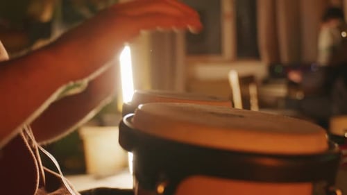 Musician Hands Playing Bongo Drums in Warmly Lit Home Recording Studio Close Up