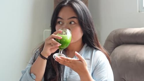 Woman Drinks Healthy Green Smoothie at Home
