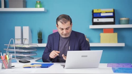 Man Answering Phone and Gesturing at Desk