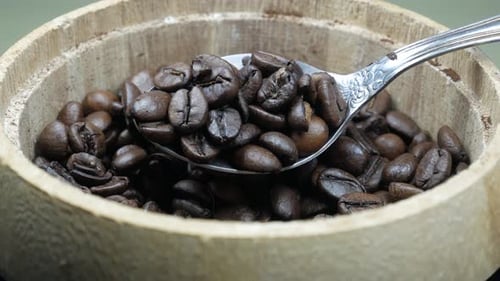Spoon Scooping Roasted Coffee Beans From Bowl