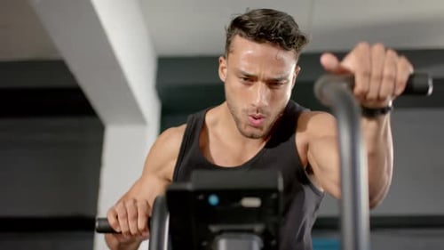 Exercising on stationary bike, man in gym focusing on intense workout