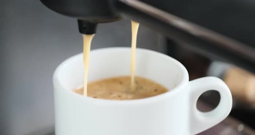 Home Espresso Making Process Coffee Stream Pouring From Machine Into Ceramic Cup