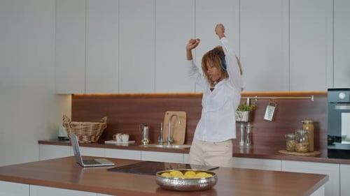 Woman Dancing with Headphones in Modern Kitchen
