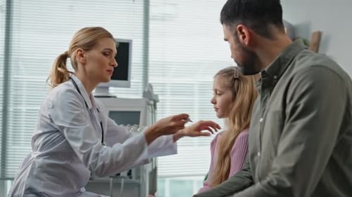 Smiling Doctor Measuring Temperature in Examination Room Father Visiting Clinic