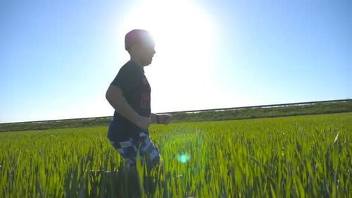 Carefree Child in Hat Jogging at the Meadow in Summer and Having Fun Happy Boy is Running Through