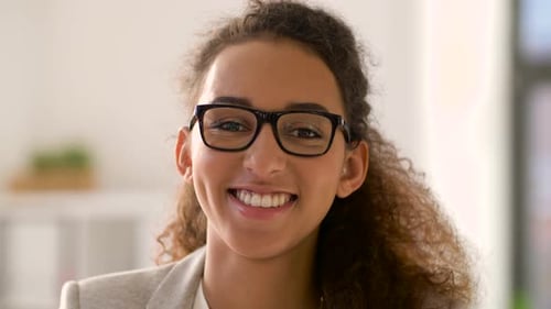 Smiling woman with curly hair wearing glasses indoors