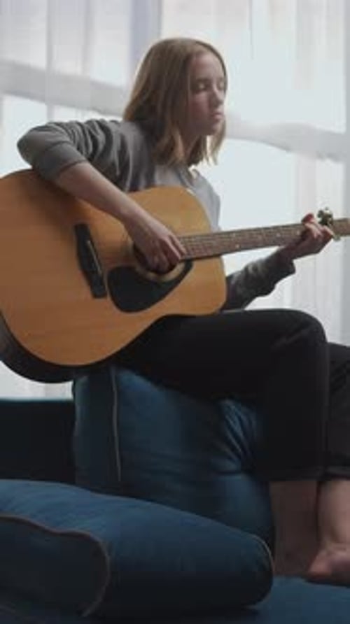 Woman Plays Acoustic Guitar Sitting on a Couch