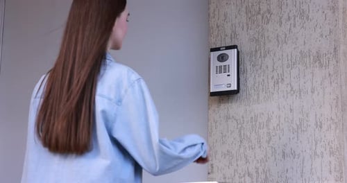 Woman pressing button on intercom panel outdoors, camera moving in