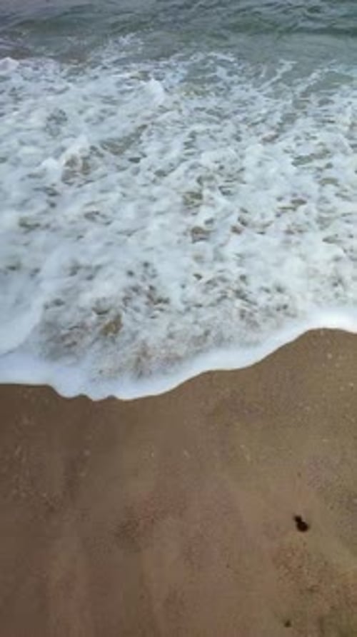 Sea Waves with White Foam Roll on the Sandy Beach of the Seashore Closeup