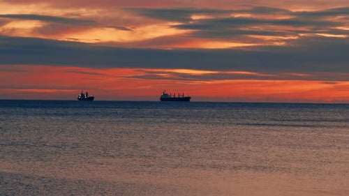Two Cargo Ships Under Sail at Sunset