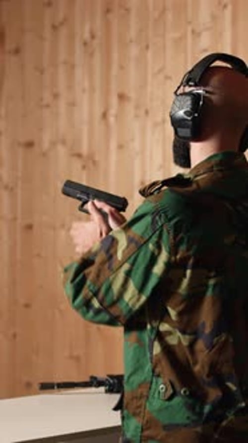 Vidéo verticale Un soldat joyeux s'entraînant avec une arme à feu exulte après avoir touché la cible avec précision