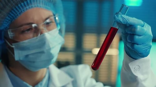 Scientist Examining Red Liquid Sample in Lab