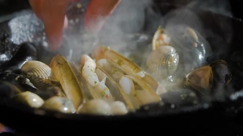 Moules et crustacés cuisent dans une poêle, puis mélangés