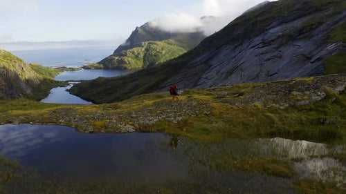 Attractive Woman Stands on Top Mountain Lake Range and Looks Around High in the Mountains