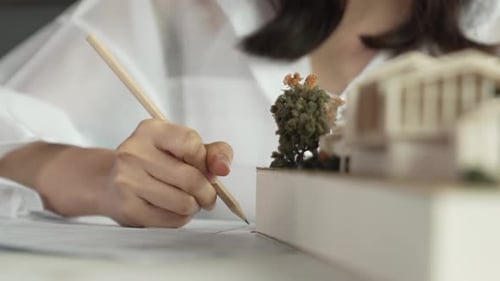 Bel architecte dessinant un plan tout en pointant vers le modèle. Manipulateur.