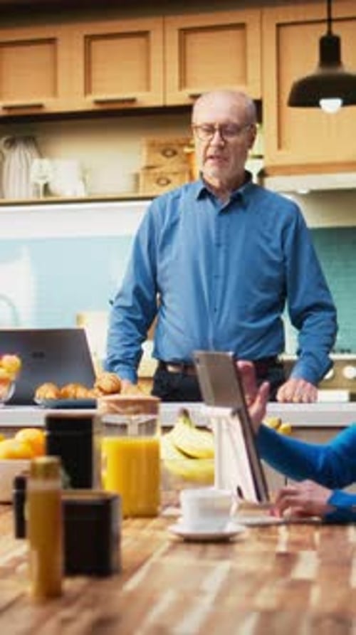 Senior Couple Enjoying Breakfast and Working in Kitchen