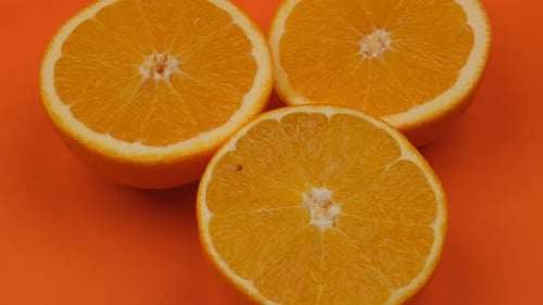 Three Orange Halves Displayed on Orange Background