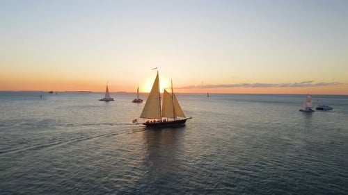 Boats sailing into sunset on ocean horizon