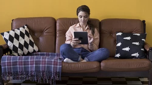 Young Woman Relaxing on Couch Using Tablet