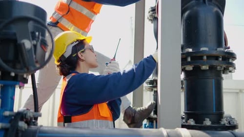 Professional female industrial engineer uses a walkie-talkie to communicate while inspecting factory