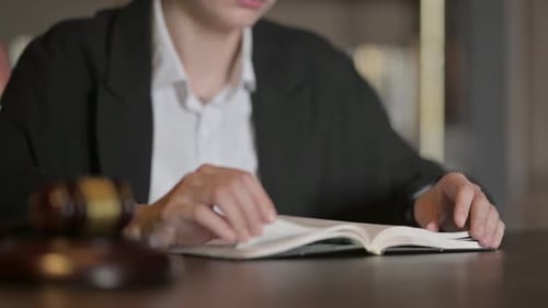 Vista aproximada de uma juíza lendo um livro de direito