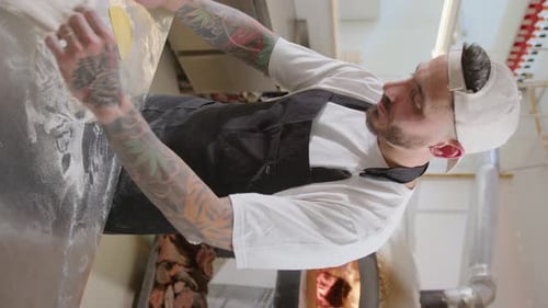 Chef Shaping Dough for Pizza Base at Kitchen Table