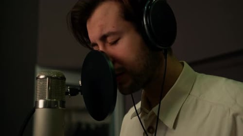 singer with headphones and microphone emotionally recording a new song in a professional studio
