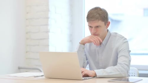 Young Adult Working on Laptop at Desk