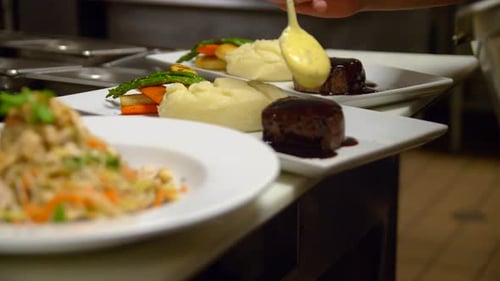 Chef plating gourmet food with sauce in kitchen