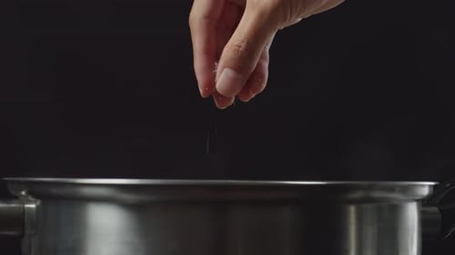 Close Up Of Chef's Hand Adding Salt In The Soup Pot. Sukiyaki Or Shabu In A Pot