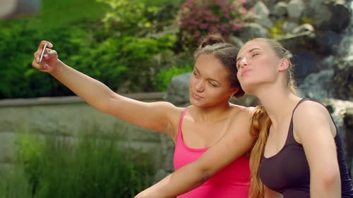 Fröhliche Millennial-Freundinnen halten Sommererinnerungen fest und machen Selfies im Park