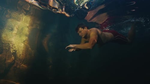 Man Dives in the Freshwater River with Sunny Rays Shining Through the Water