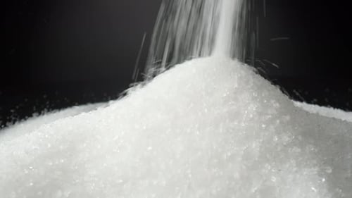 White sugar delicately cascading onto a sleek black background