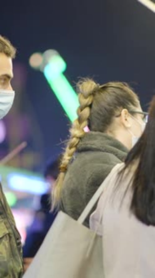 People in Protective Surgical Masks at Valencia Country Funfair at Night