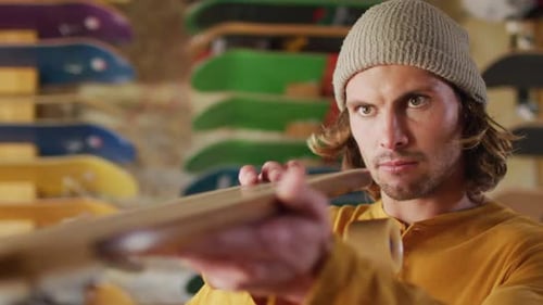 Video of caucasian male skateboarder fixing skateboard in skate shop