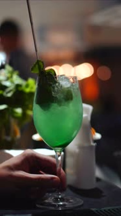 Bartender is making green summer cocktails with fresh mint leaves and lime