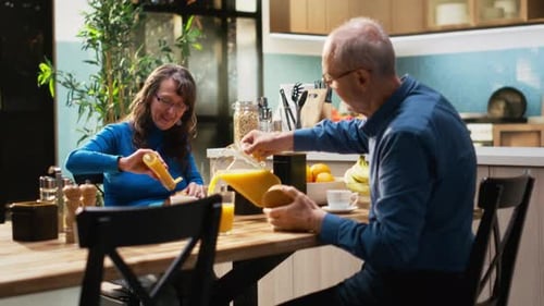 Senior Couple Enjoys Orange Juice at Kitchen Table