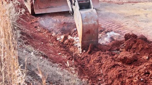 Excavatrice creusant dans le sol rouge pour défricher le terrain pour la construction