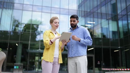 Man and Woman Discussing Tablet Outside Office Building