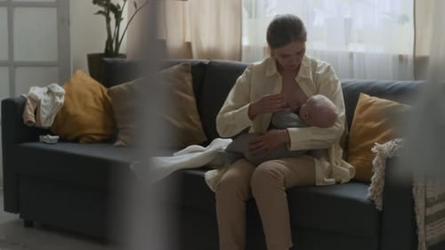 Woman Breastfeeding Baby on Sofa at Home
